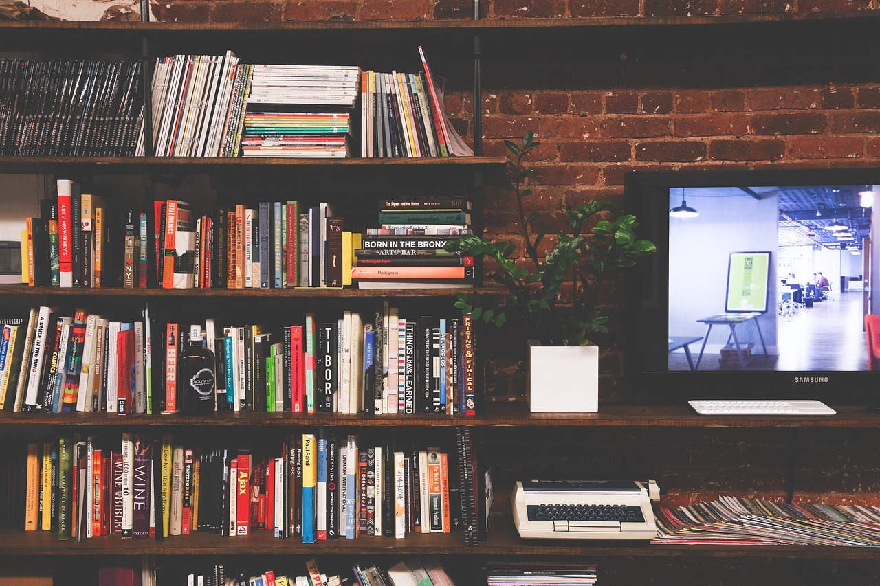 image of a bookcase, a desk with a computer on it