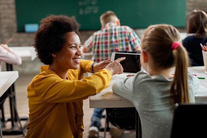 teacher holding a tablet and explaining to a student