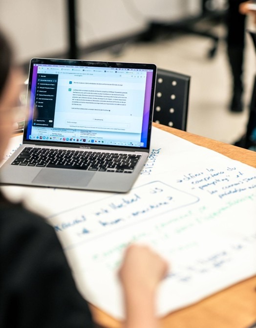 Une enseignante utilise un outil l'IAg sur son ordinateur portable afin de la guider dans un travail collaboratif.