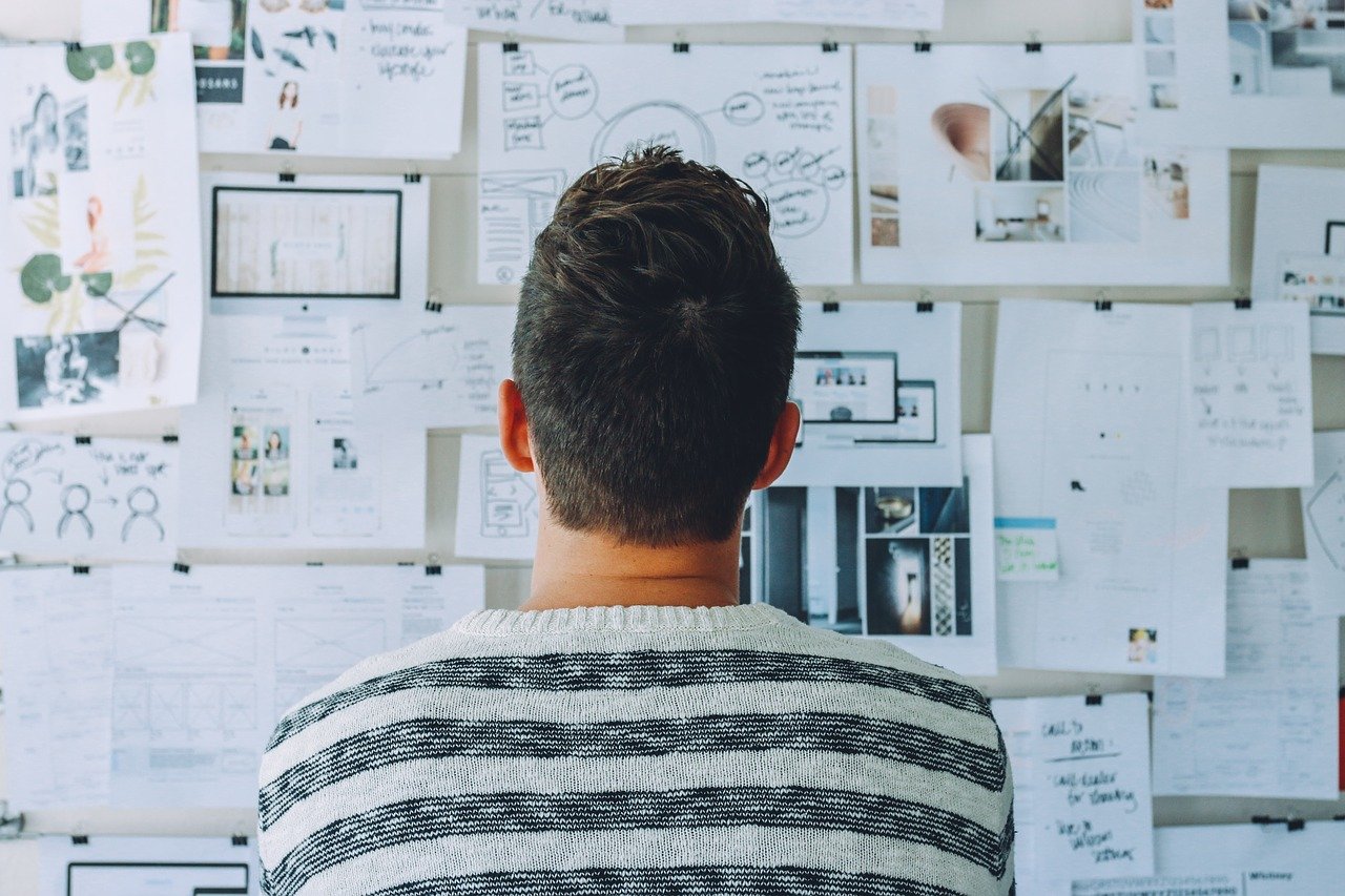 Man looking at a wall with pictures and writing.